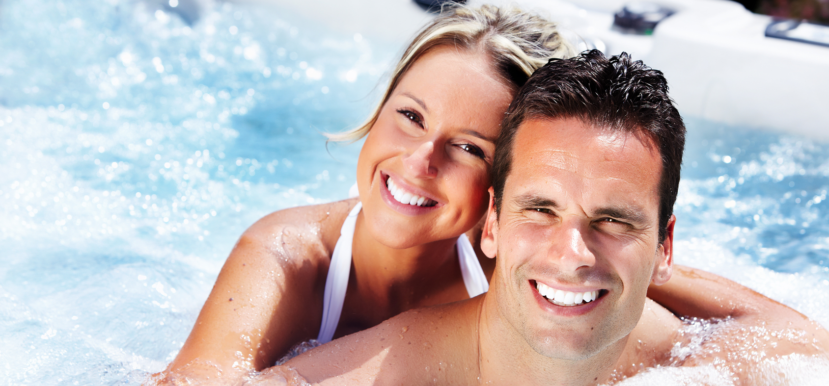 A man and a woman enjoying the bubbles of a hot tub